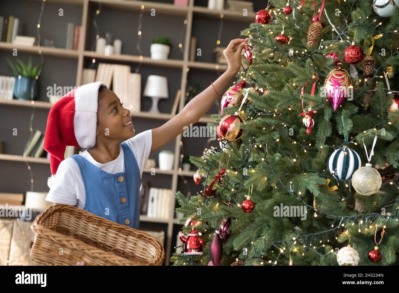 Petite fille de race mixte décorant arbre de Noël. Banque D'Images