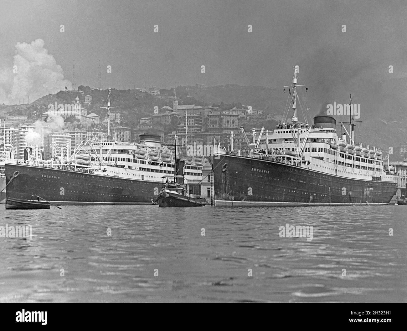 Le port de Trieste, Italie dans les années 1930.Deux navires de mer sont dans le port – les navires-sœurs MS Saturnia (à gauche) et MS Vulcania (à droite), qui, avec de la fumée et un remorqueur aidant, sont sur le point de quitter le port.Mme Saturnia était un paquebot italien lancé en 1925.Elle était la sœur du navire MS Vulcania, lancée l'année suivante – une photographie vintage des années 1930. Banque D'Images