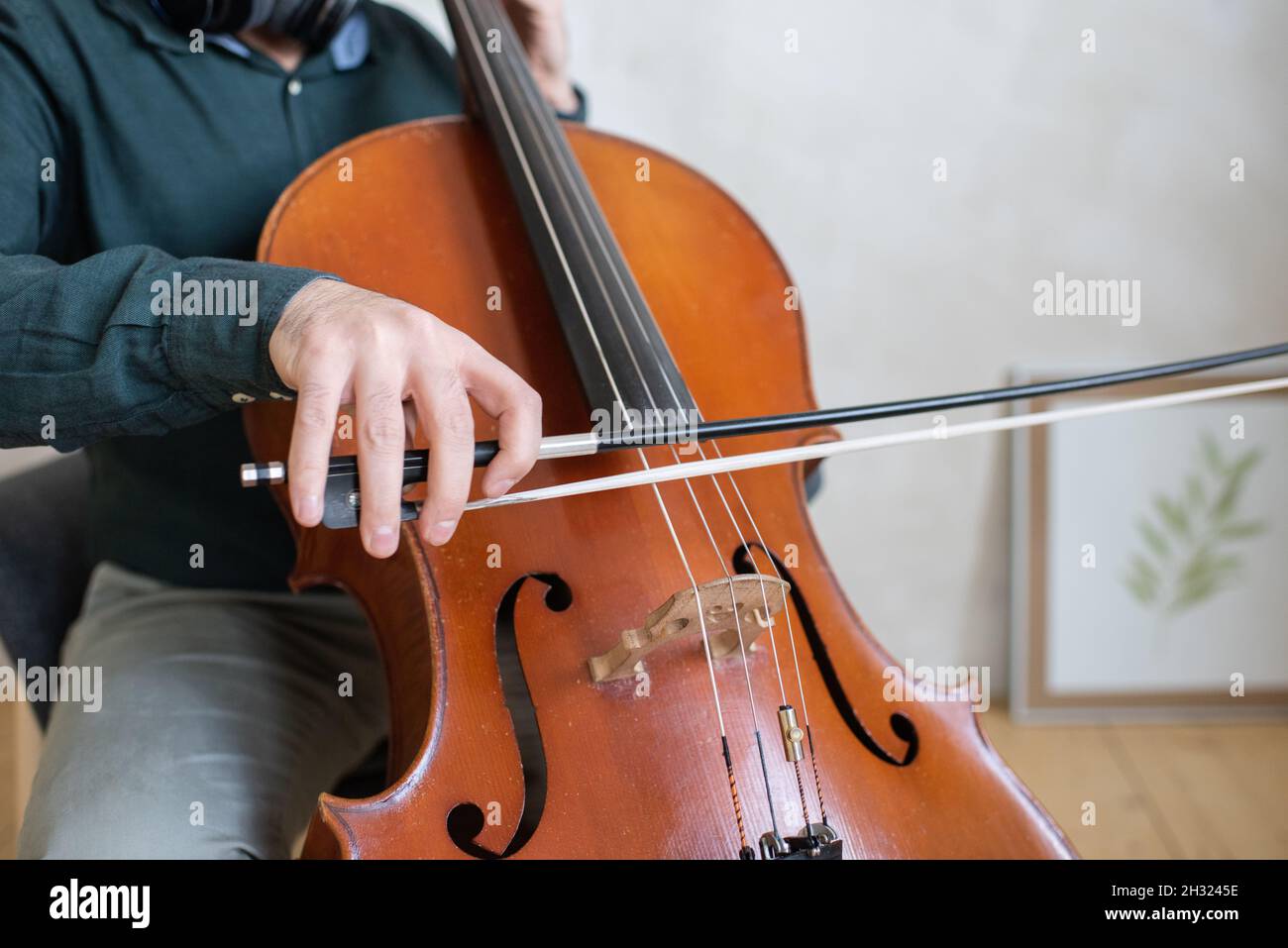 Main du jeune violoncelle qui glisse le violon sur les cordes tout en exécutant un morceau de musique devant l'appareil photo Banque D'Images