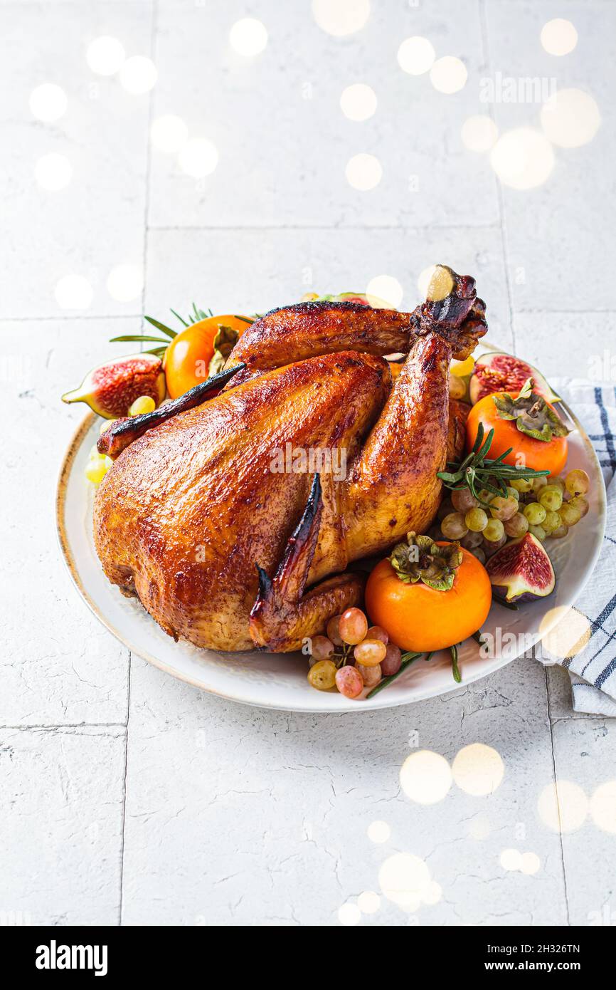 Poulet entier rôti de Noël servi avec des fruits sur une assiette. Banque D'Images