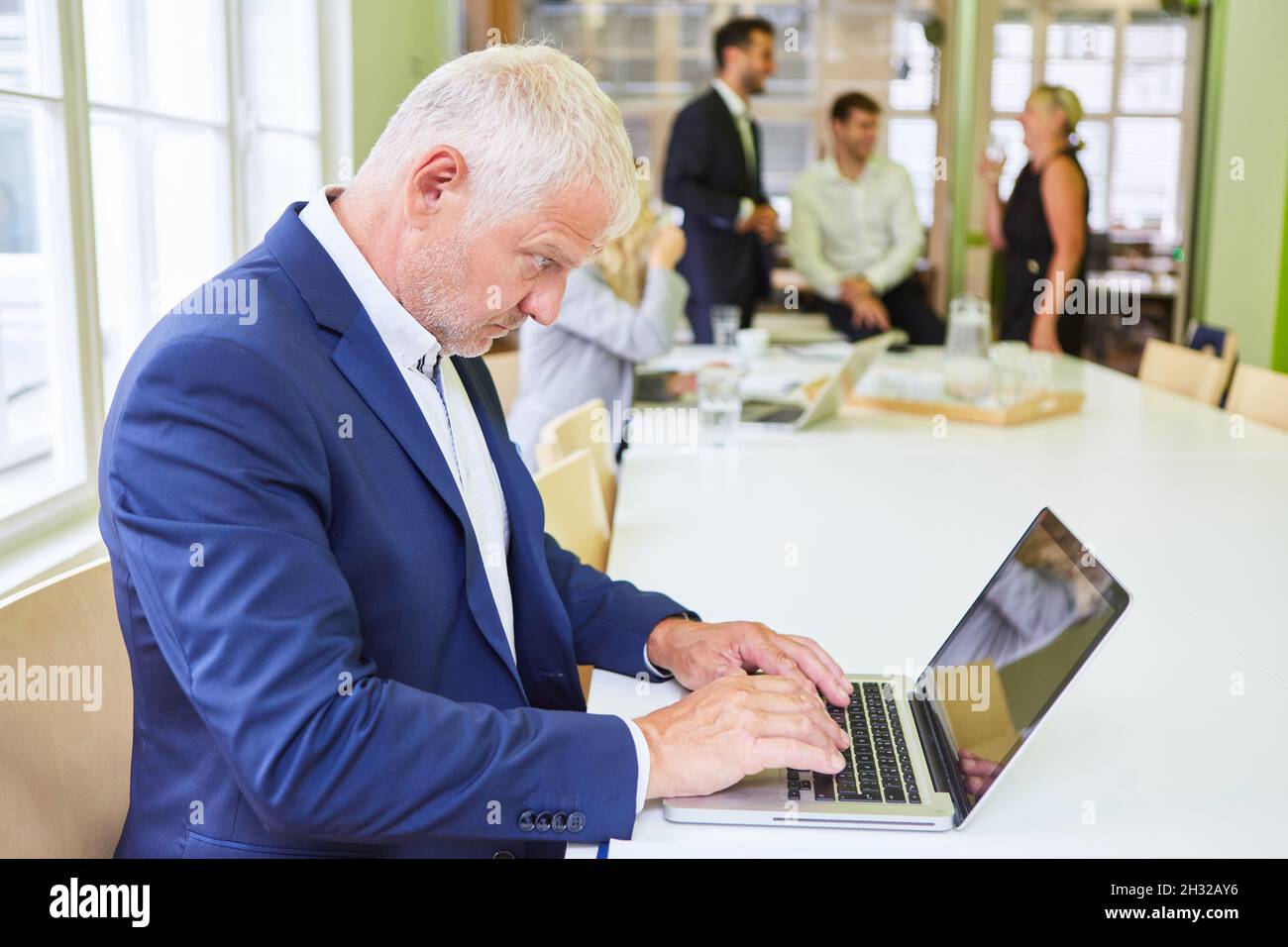 Homme d'affaires mature en tant que directeur ou consultant écrit sur un ordinateur portable Banque D'Images