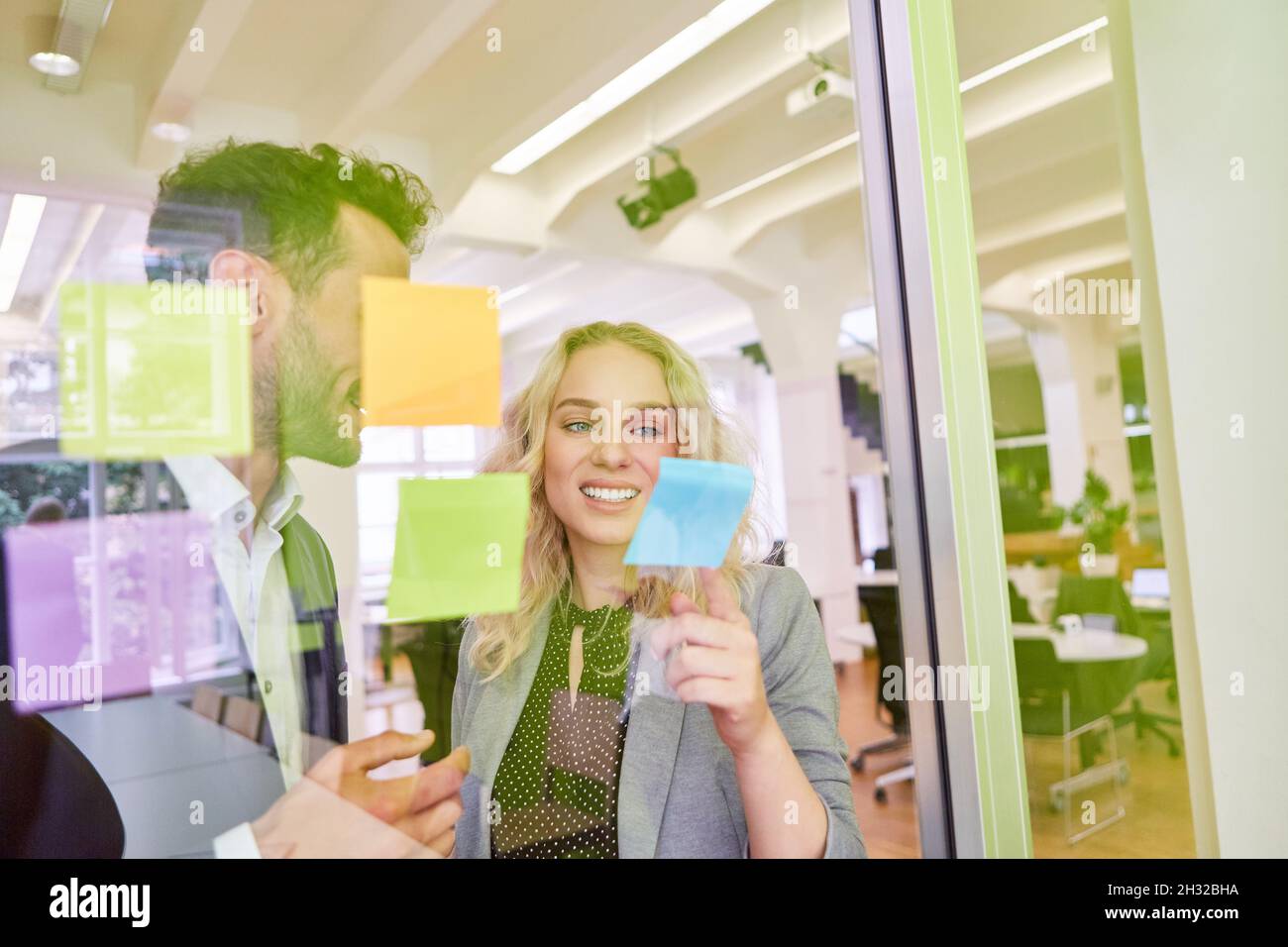 Les jeunes gens d'affaires remue-méninges dans un atelier créatif avec des notes adhésives sur le verre Banque D'Images