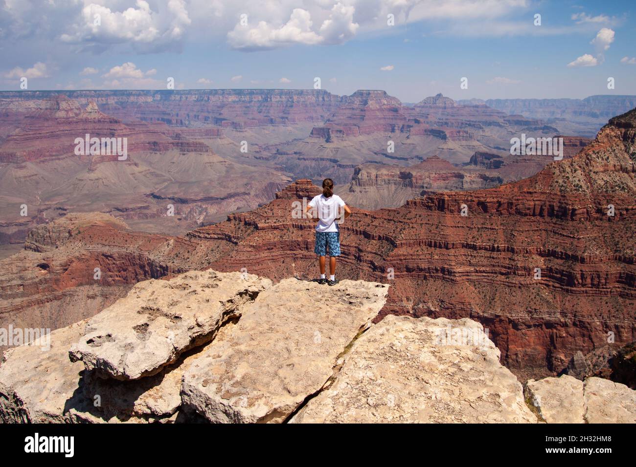 Jeune caucasien avec de longs cheveux se tiennent sur le bord de la roche et admirez le panorama du Grand Canyon vue arrière | Parc national du Grand Canyon, Arizona, États-Unis Banque D'Images