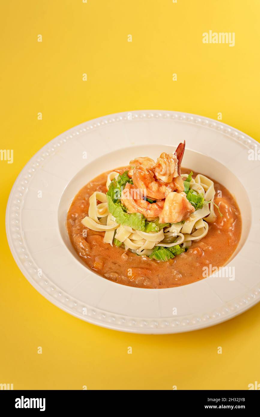 Spaghetti aux crevettes et légumes sur plat blanc, sauce tomate Banque D'Images