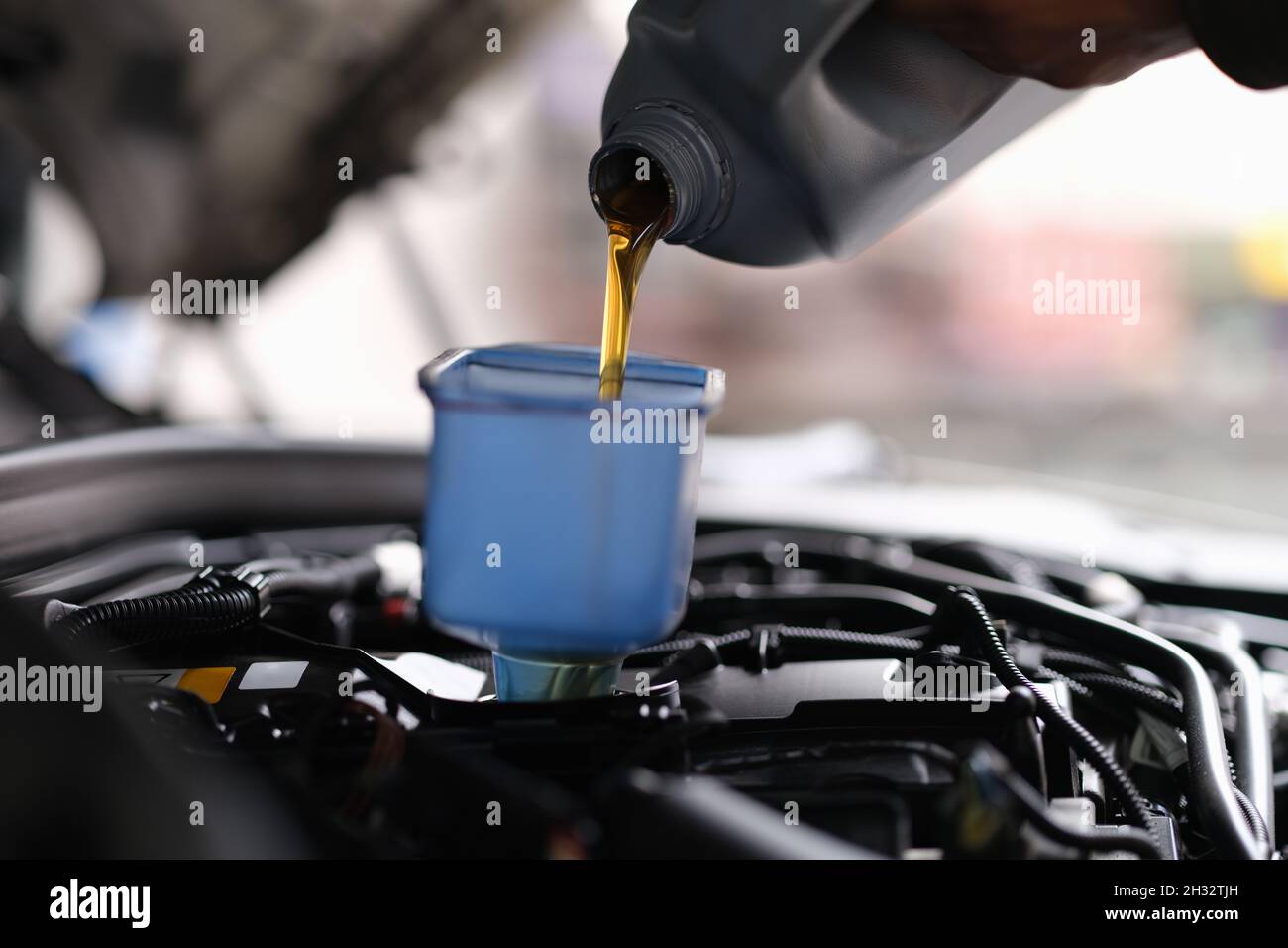 L'huile de machine pour une voiture est versée dans un récipient Banque D'Images