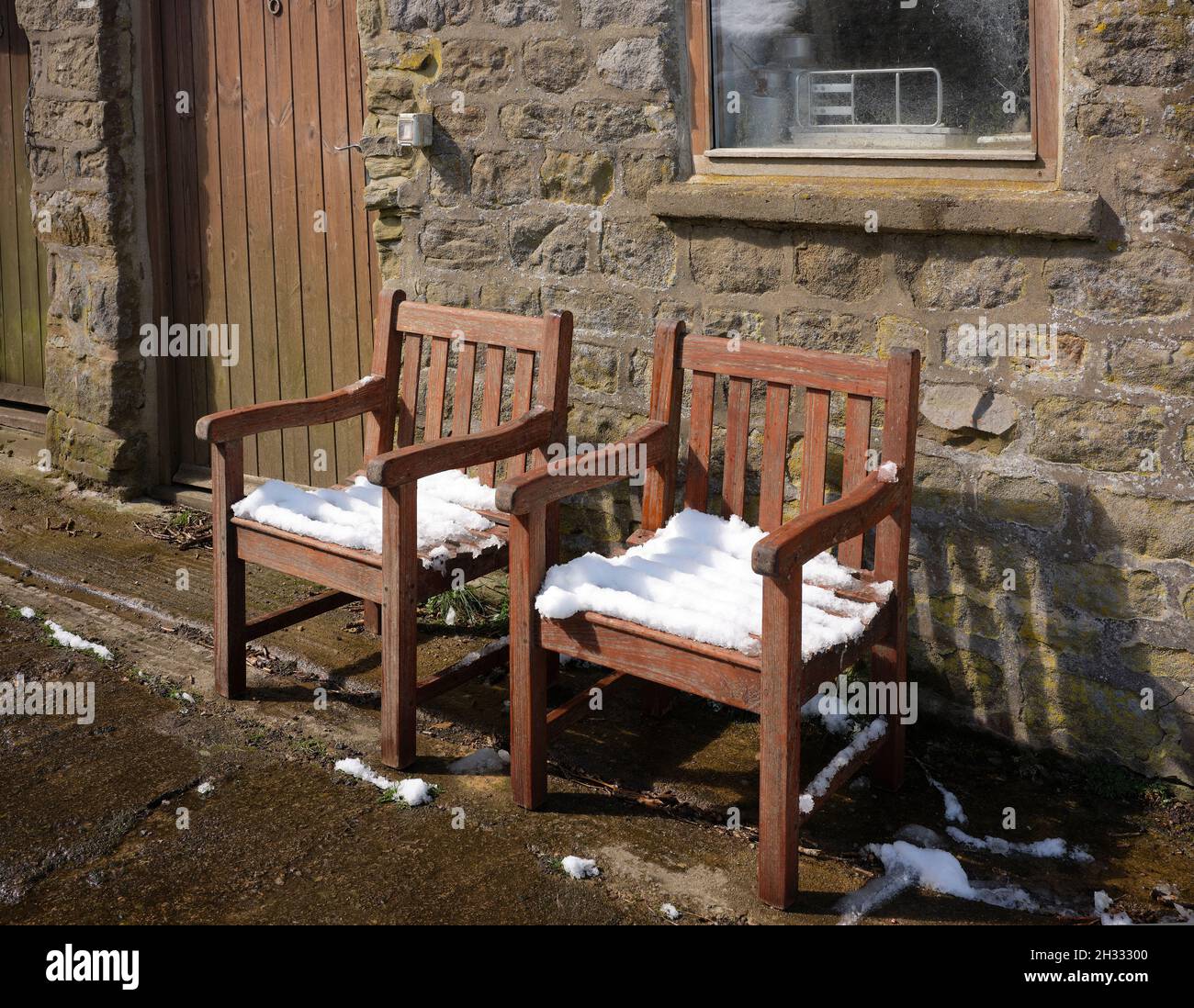 Les chaises de jardin en bois sèchent au soleil d'avril après une chute de neige inattendue au printemps Banque D'Images