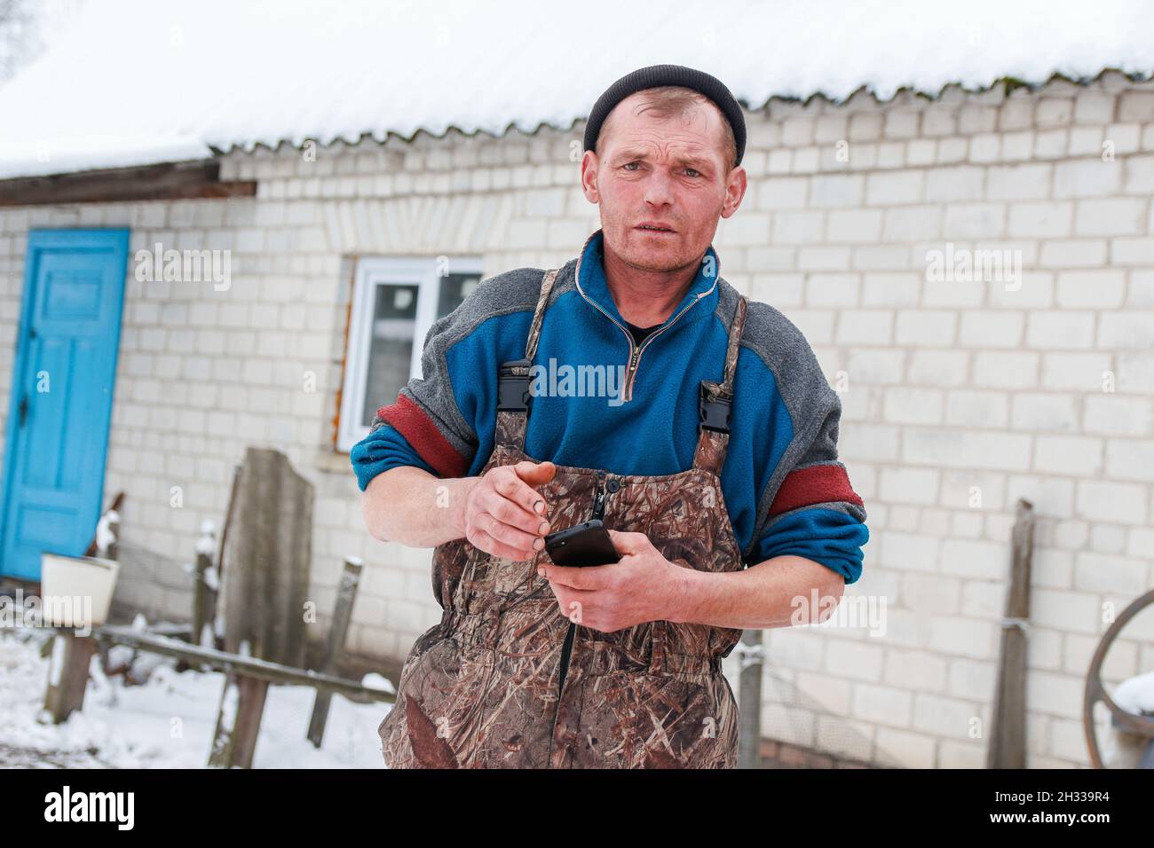 Jeune homme russe debout à l'extérieur sur fond de campagne d'hiver.Téléphone de garde du travailleur de la construction.Ouvrier caucasien 40 ans, portrait. Banque D'Images