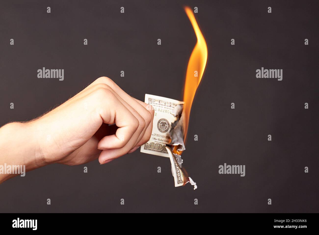 L'homme tient à brûler des billets de cent dollars. Banque D'Images