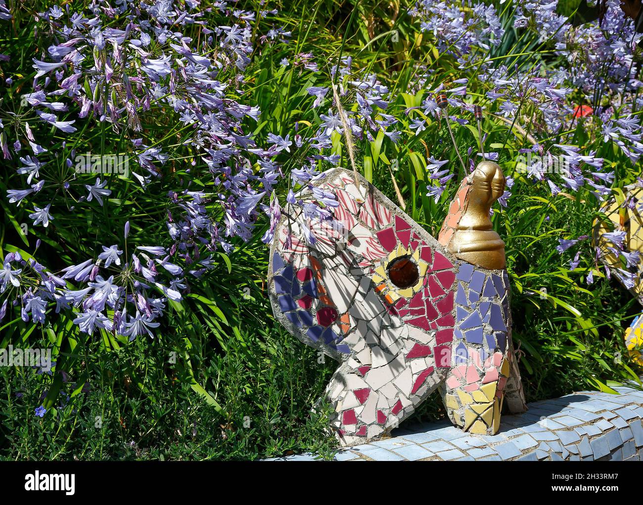 scène de jardin, grand papillon en mosaïque, fleurs violettes, morceaux de céramique, coloré,Creative, art, The Giants House, Akaroa ; Nouvelle-Zélande Banque D'Images