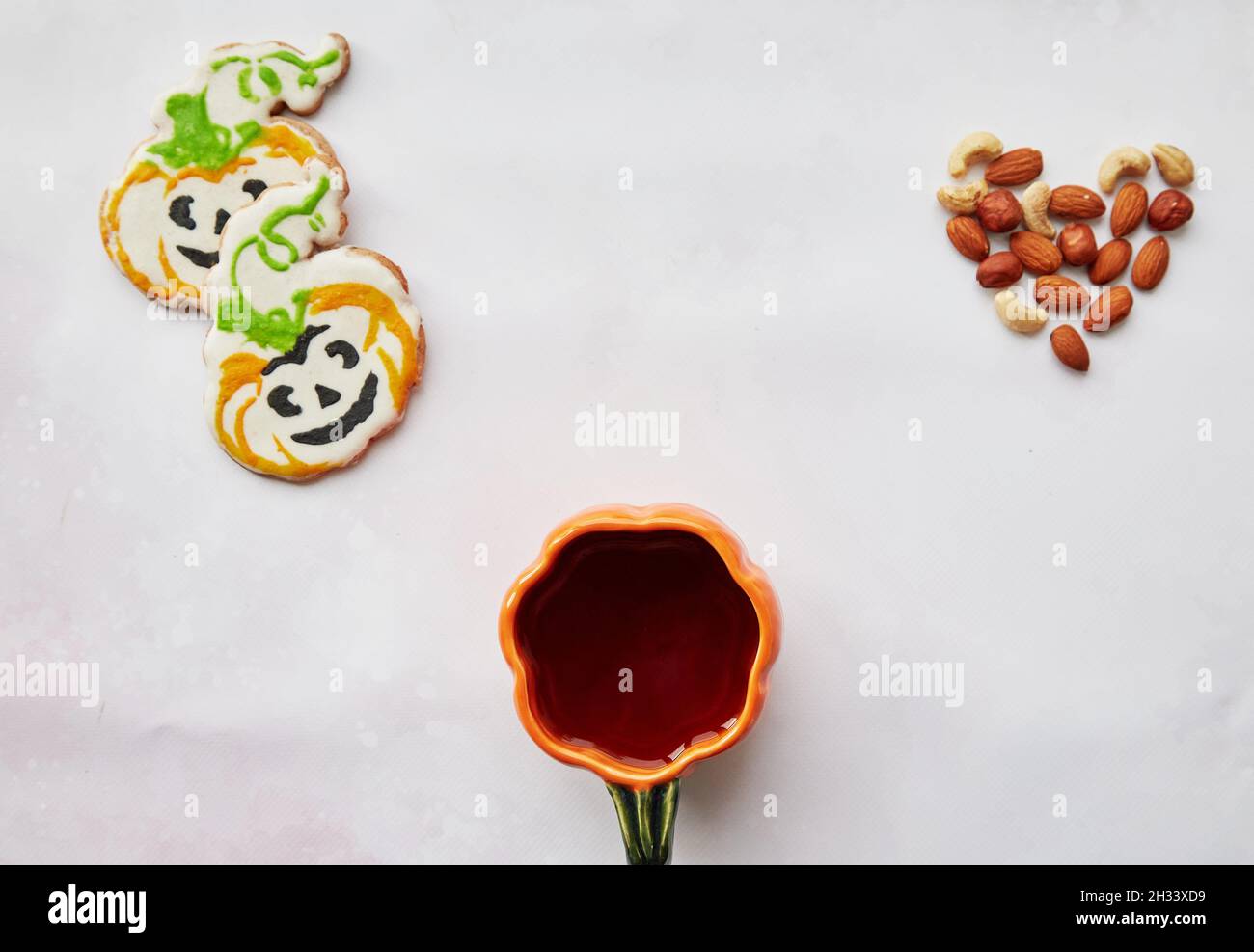 Halloween fond créatif : tasse de citrouille et biscuits faits maison en forme de citrouilles mignonnes et coeur d'amandes.Concept Trick or Treat.Esthétique automne Banque D'Images