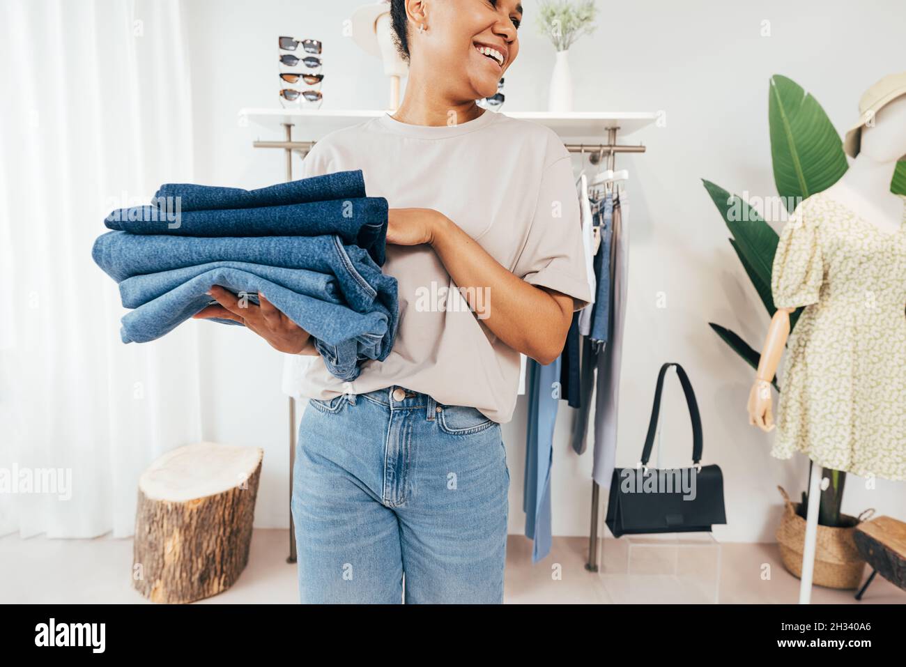 Coupe courte d'une jeune femme de vente tenant une pile de vêtements pliés et regardant loin Banque D'Images