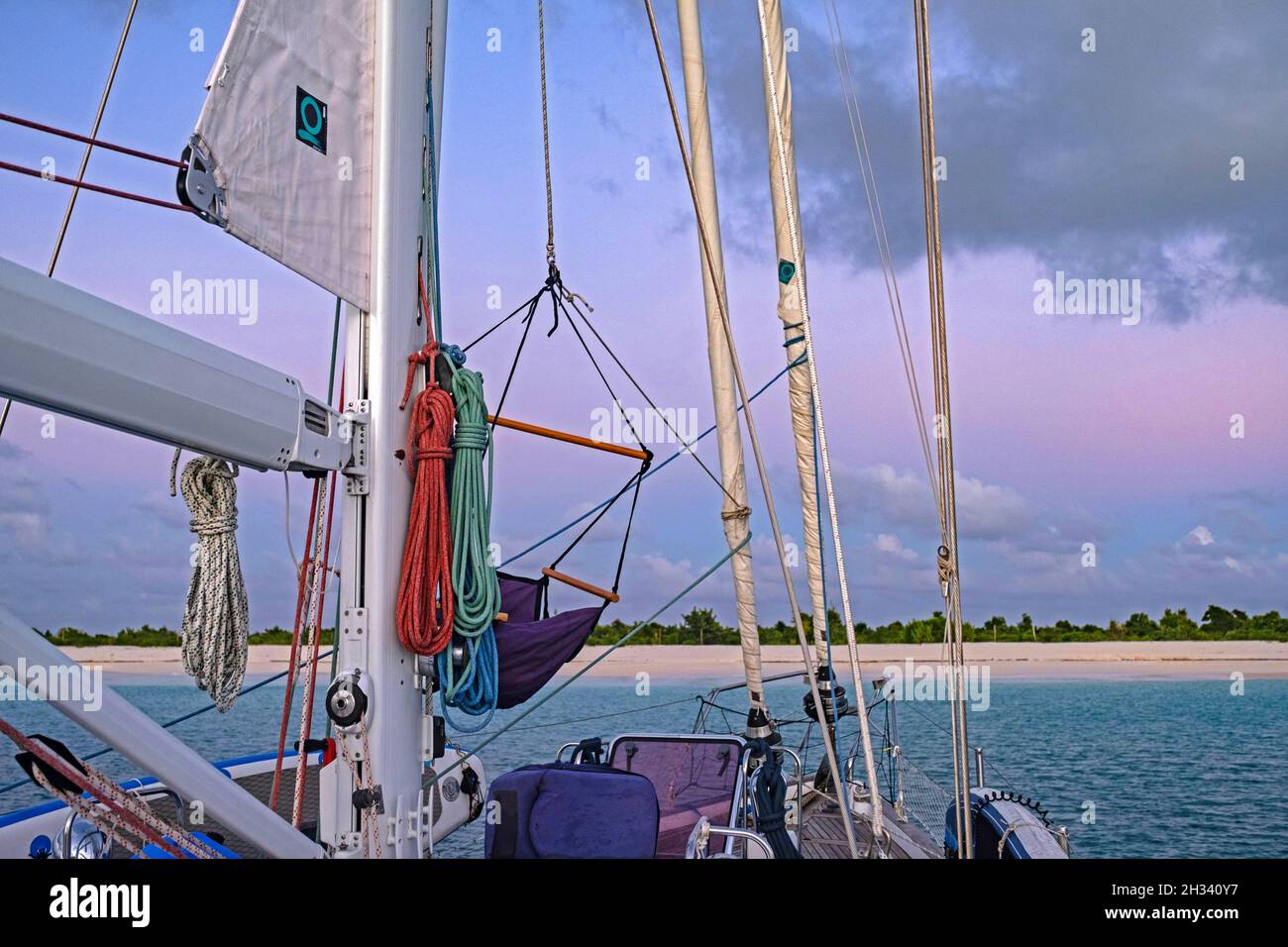 Bateau à voile / yacht / voilier ancré en face de l'île de Barbuda au coucher du soleil, Antilles dans la mer des Caraïbes Banque D'Images