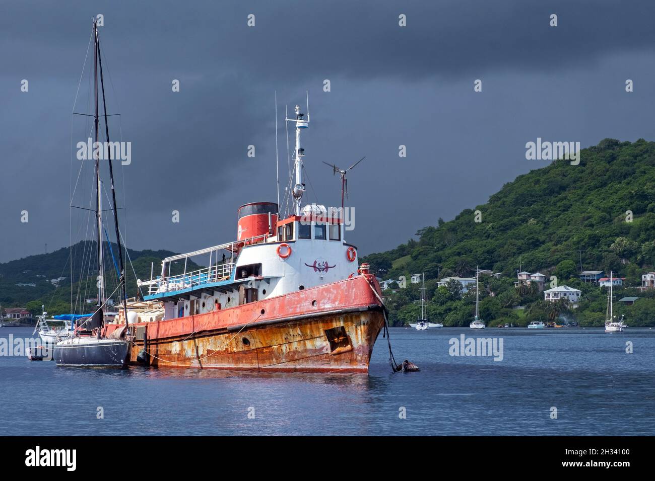 Vieux navire rouillé parmi les voiliers attendant la fin de la saison des ouragans dans la baie de Woburn, à Saint George, sur l'île de Grenade, dans la mer des Caraïbes Banque D'Images