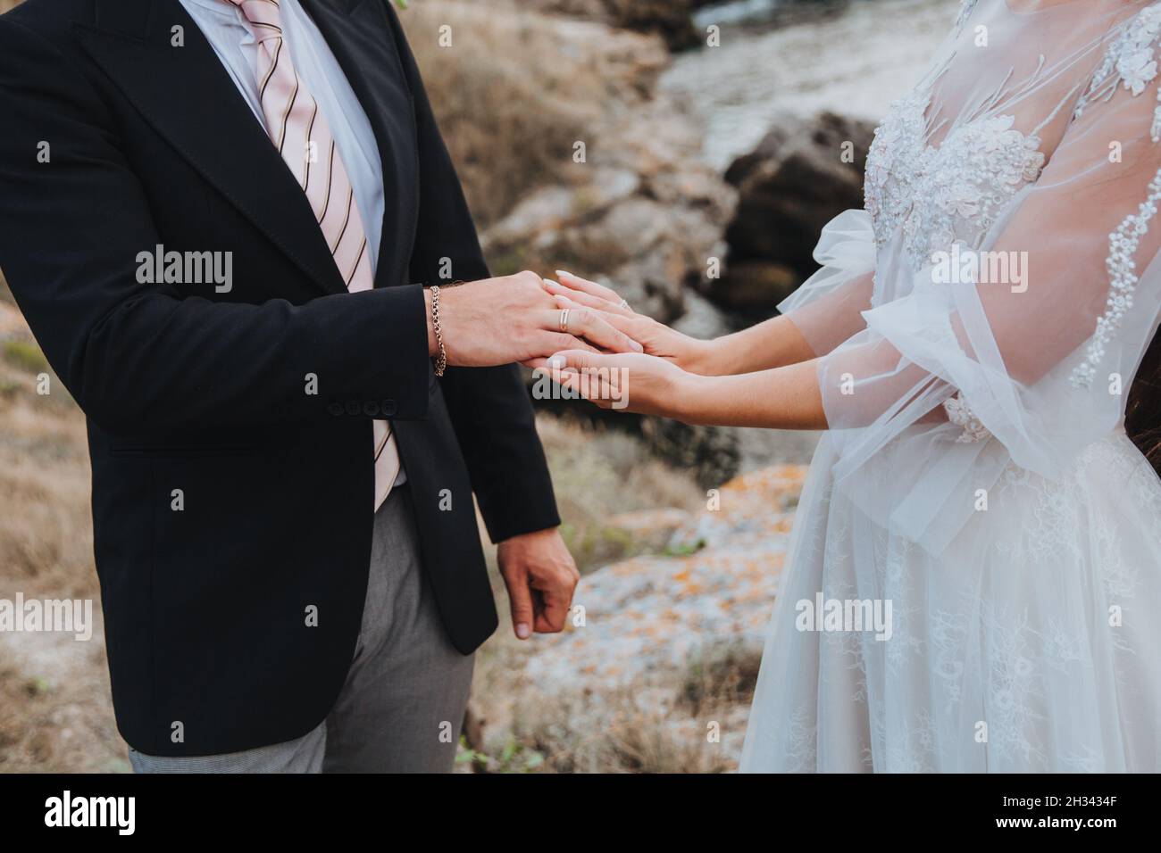 Une femme dans une belle robe blanche tient un homme vêtu d'un costume à la main, beau moment romantique entre deux amoureux Banque D'Images