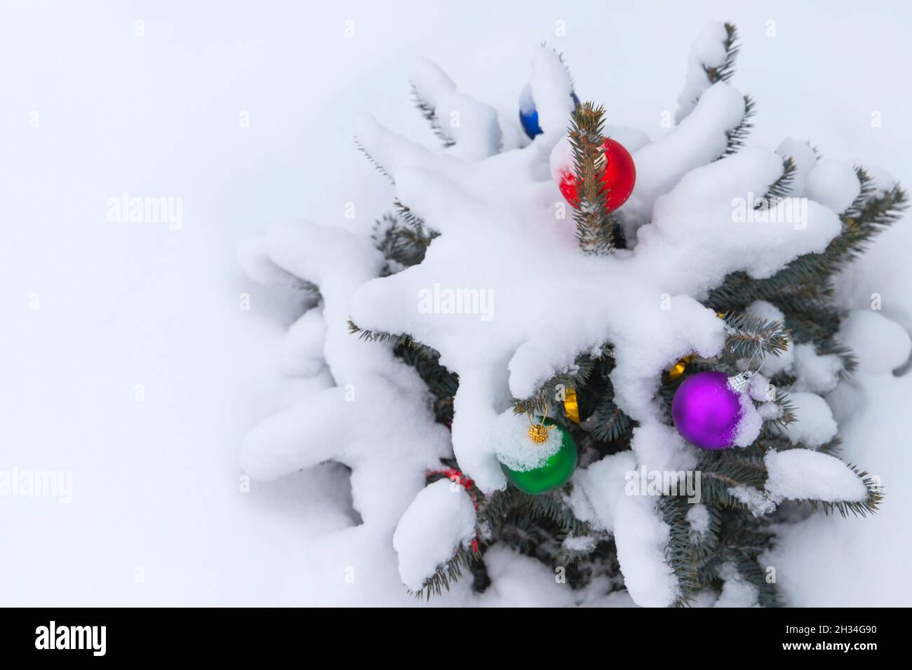 Petit arbre de Noël recouvert de neige avec des boules colorées de décoration Banque D'Images
