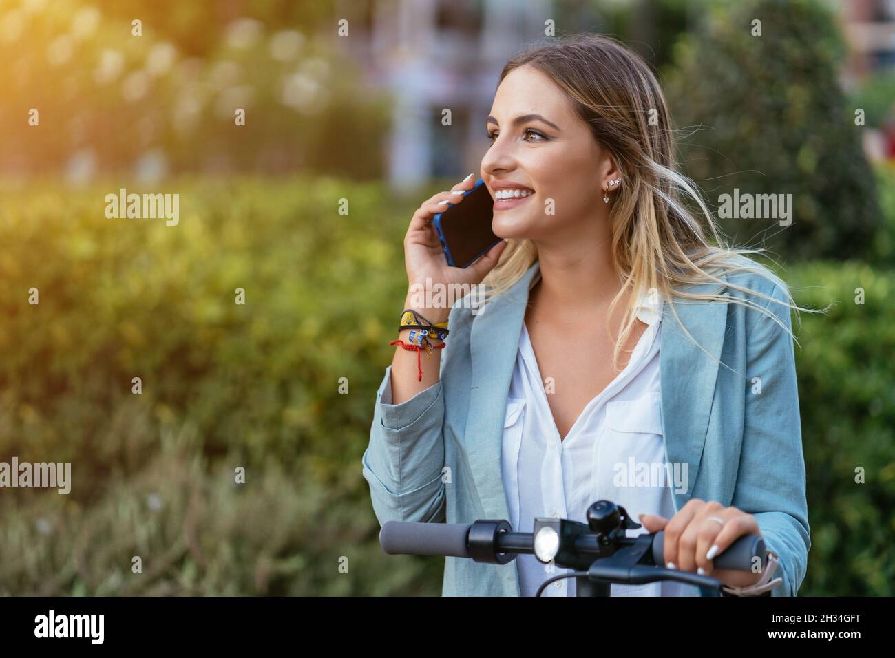 Femme d'affaires parlant sur un smartphone sur un scooter électrique Banque D'Images