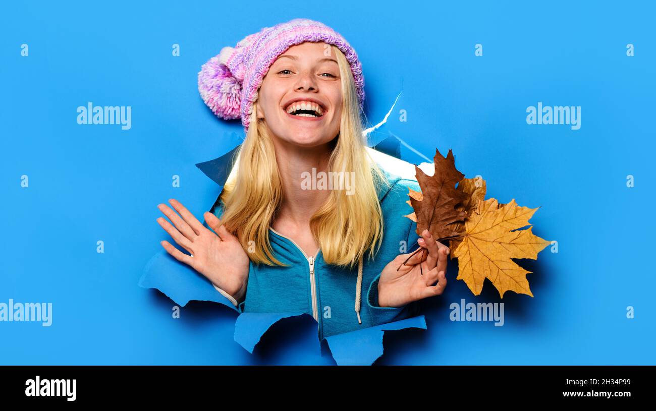 Femme souriante en bonnet tricoté regardant à travers le trou de papier.Femme mode pour l'automne.Remise.Ventes saisonnières. Banque D'Images