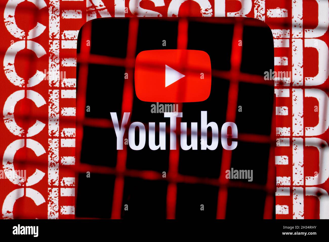 Logo YouTube sur l'écran du smartphone derrière les barres sur l'arrière-plan avec l'inscription censurée. Banque D'Images