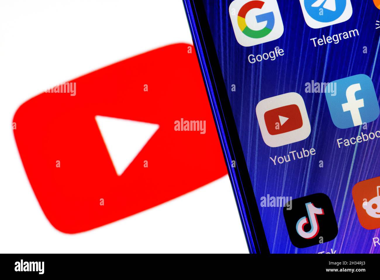 L'icône de l'application de la plate-forme de médias sociaux Youtube parmi d'autres applications sur l'écran du smartphone.En arrière-plan se trouve le logo Youtube. Banque D'Images