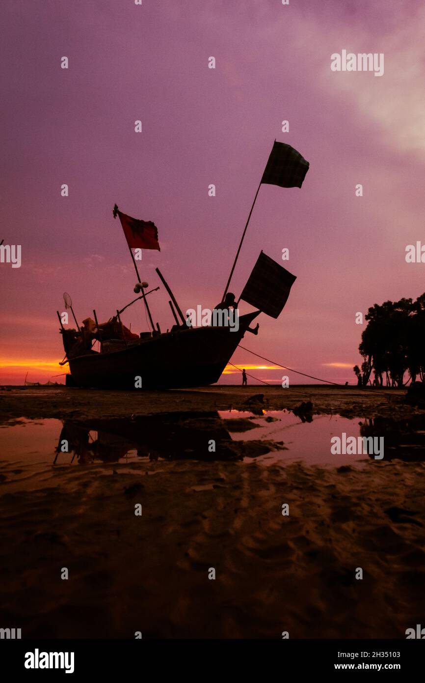 le bateau de pêche attend la marée haute au coucher du soleil. Banque D'Images