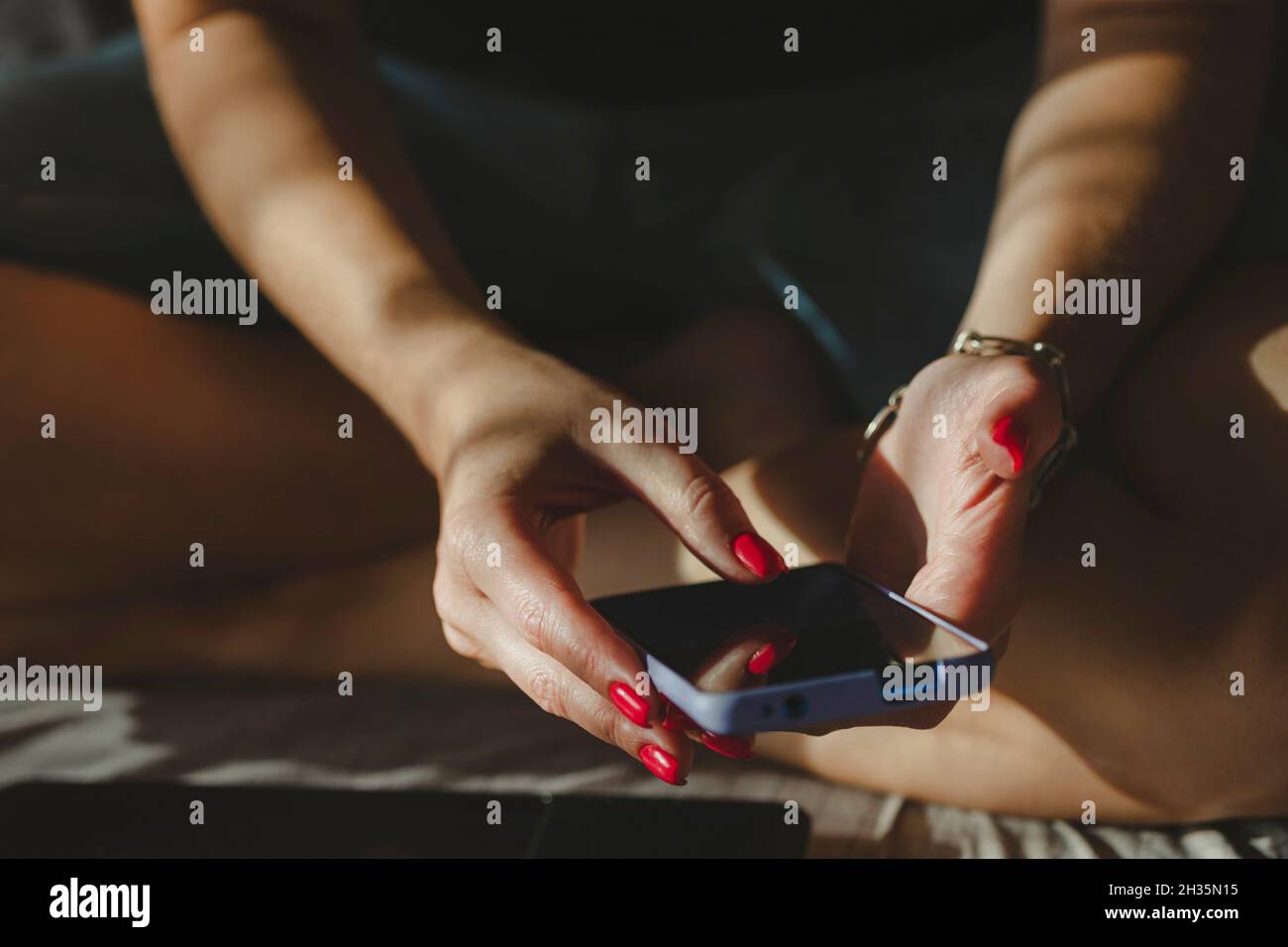 Femme textant à l'aide d'un téléphone portable, mains avec vernis à ongles rouge manucure dans le cadre. Achats en ligne. Banque D'Images