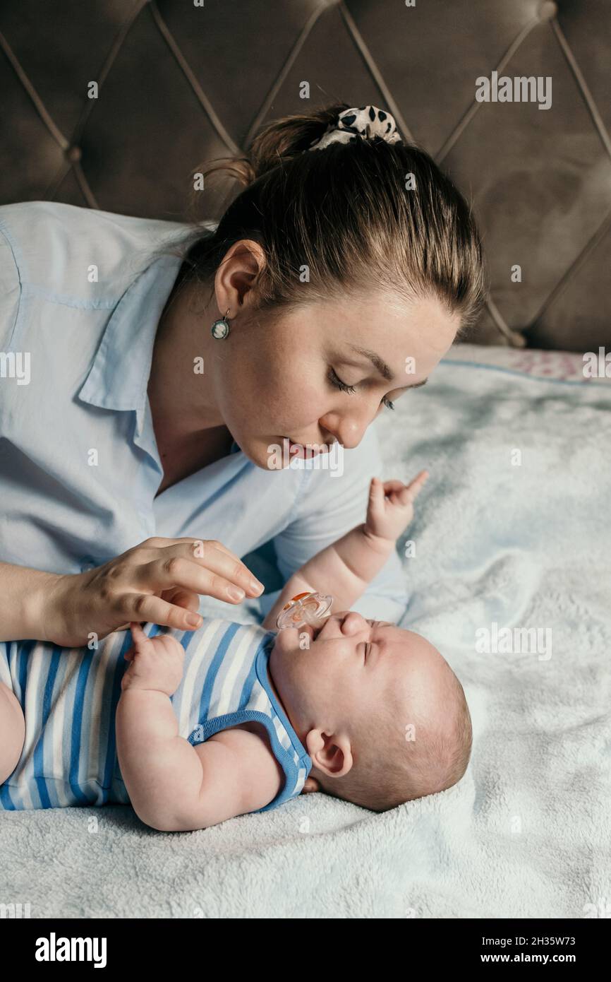 Une jeune mère qui se coulait avec son bébé garçon au lit Banque D'Images