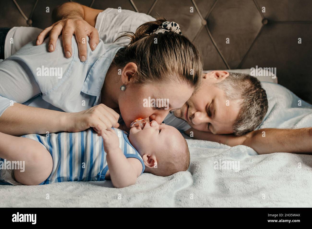 La mère et le père se couchant avec leur nouveau-né bébé garçon au lit Banque D'Images