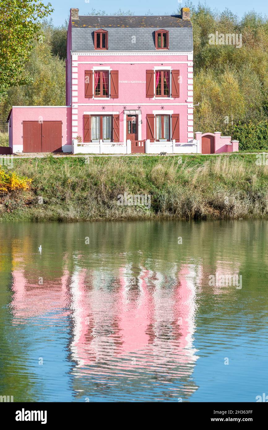 Maison rose sur le bord du canal, réflexions sur l'eau.Saint-Valery, Baie de somme, France Banque D'Images