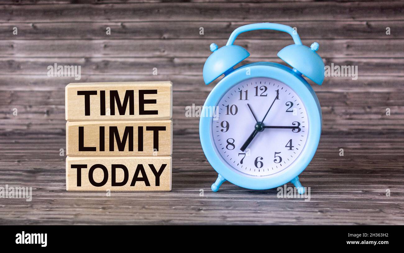 Le message DE LA LIMITE DE TEMPS AUJOURD'HUI est écrit sur des blocs de bois, à côté d'un réveil sur une table en bois. Banque D'Images