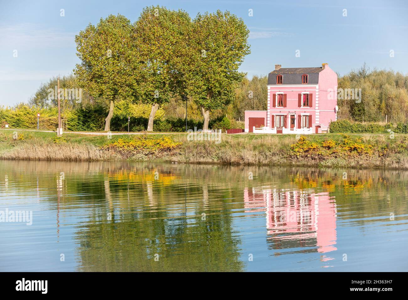 Maison rose sur le bord du canal, réflexions sur l'eau.Saint-Valery, Baie de somme, France Banque D'Images