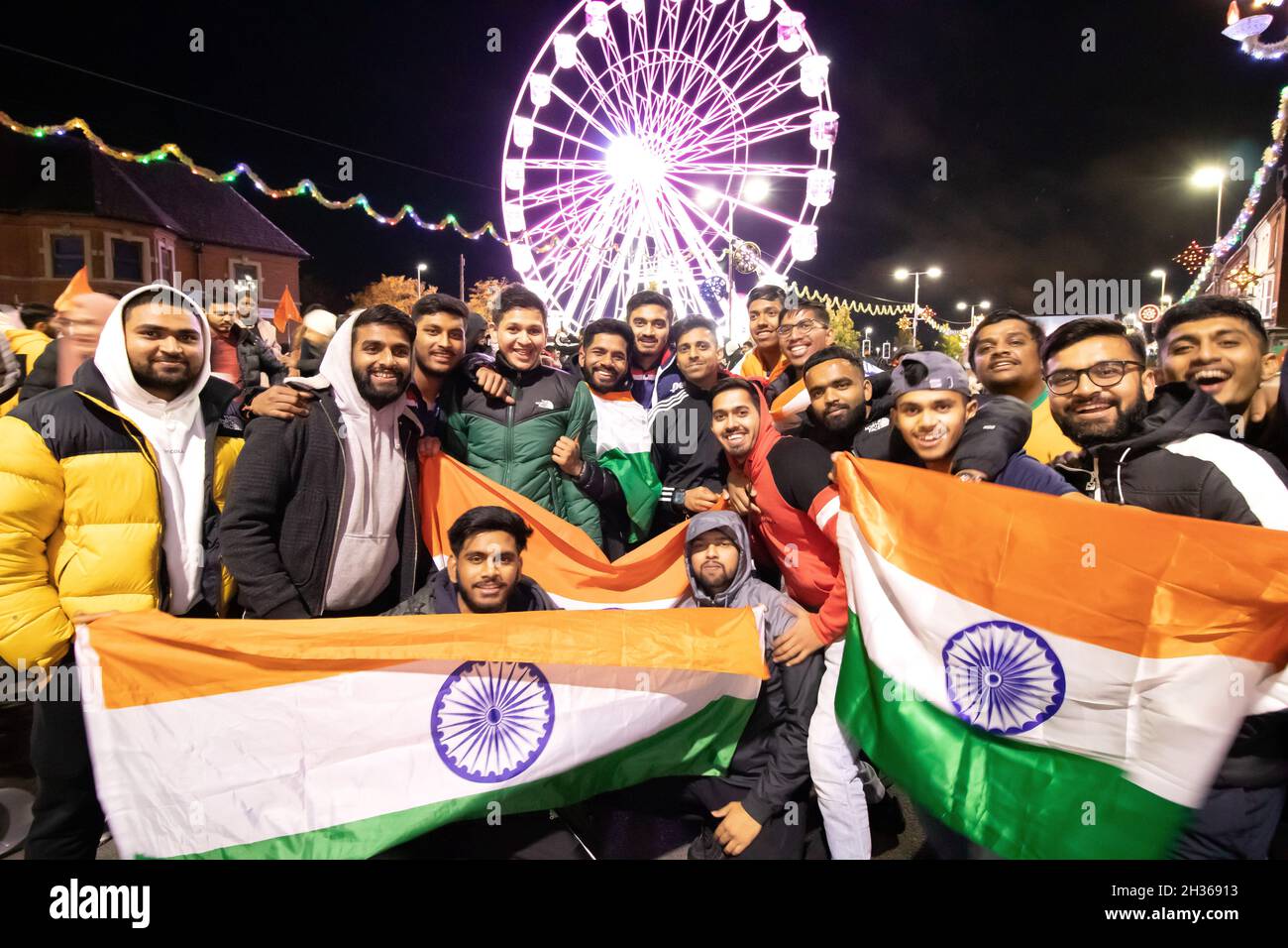 Le voyant Diwali s'allume chaque année à Leicester.Des milliers de personnes ont essaié dans le Golden Mile la région de Leicester le long de la route Belgrave pour célébrer le début du festival.Le festival est l'un des plus grands festivals de Diwali en Europe.Un grand groupe de jeunes hommes avec des drapeaux pose devant la roue du Festival de lumière sur le Golden Mile. Banque D'Images