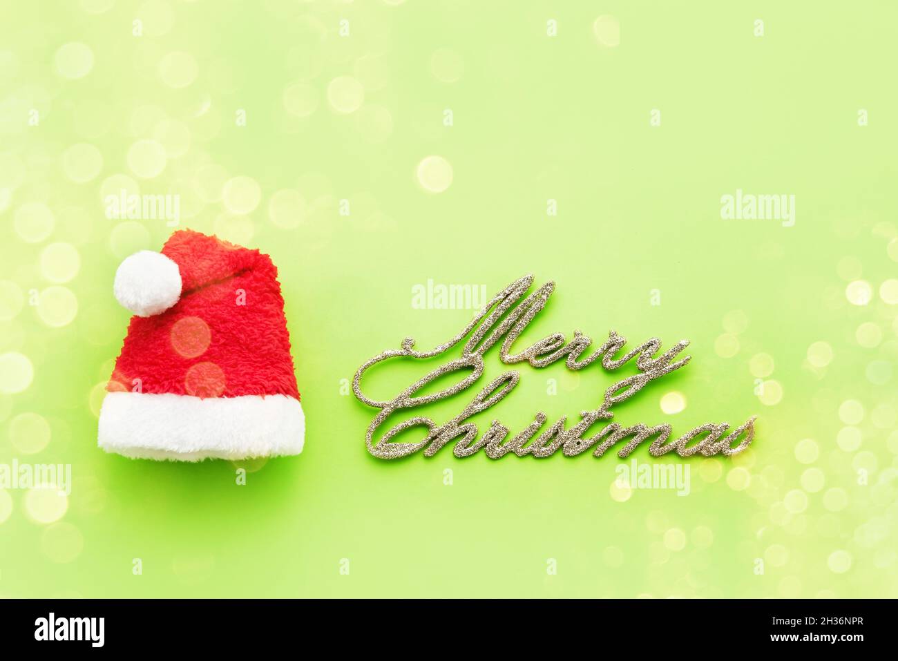 Arrière-plan de Noël.Texte Joyeux Noël et un petit chapeau de père Noël sur fond vert clair.Vue de dessus Banque D'Images