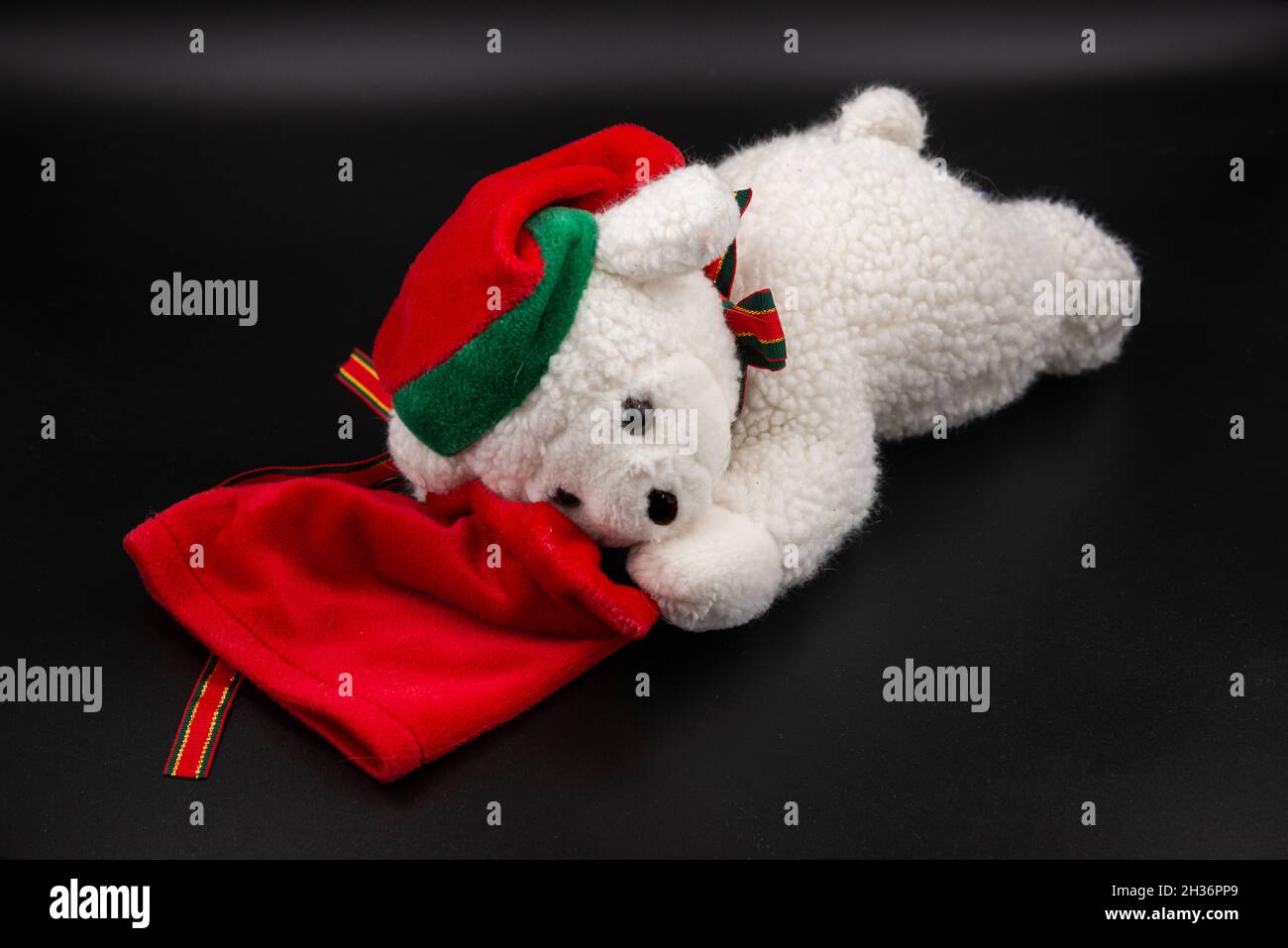 Jouet ours blanc de Noël avec chapeau nain rouge et sac cadeau rouge isolé sur fond noir Banque D'Images