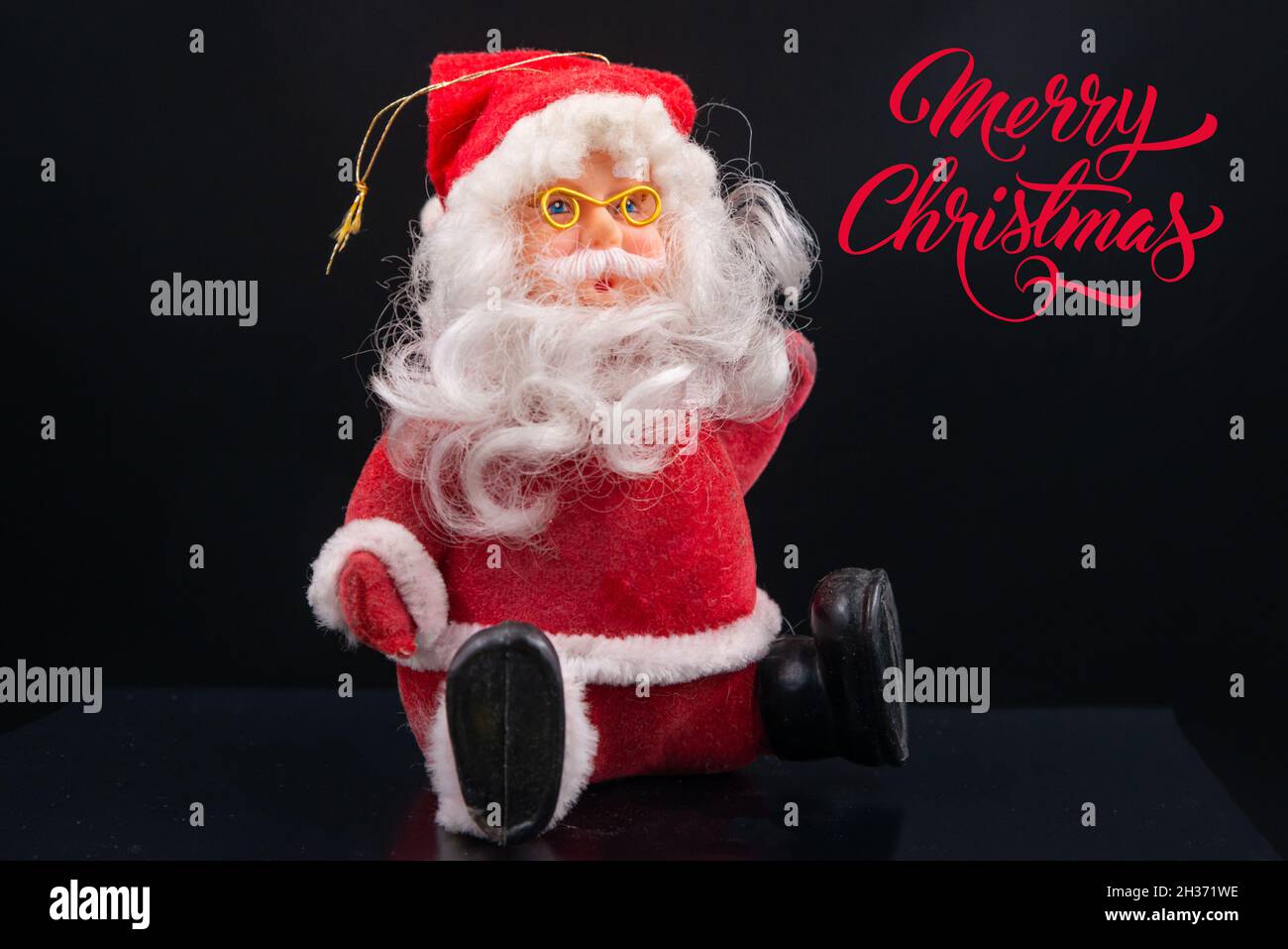 carte de noël avec jouets du père noël avec costume et chapeau rouge, barbe blanche et lunettes dorées isolées sur fond noir.Joyeux Noël Banque D'Images