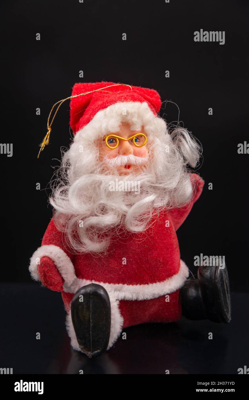 jouets du père noël avec costume et chapeau rouge et barbe blanche et lunettes dorées isolées sur fond noir Banque D'Images