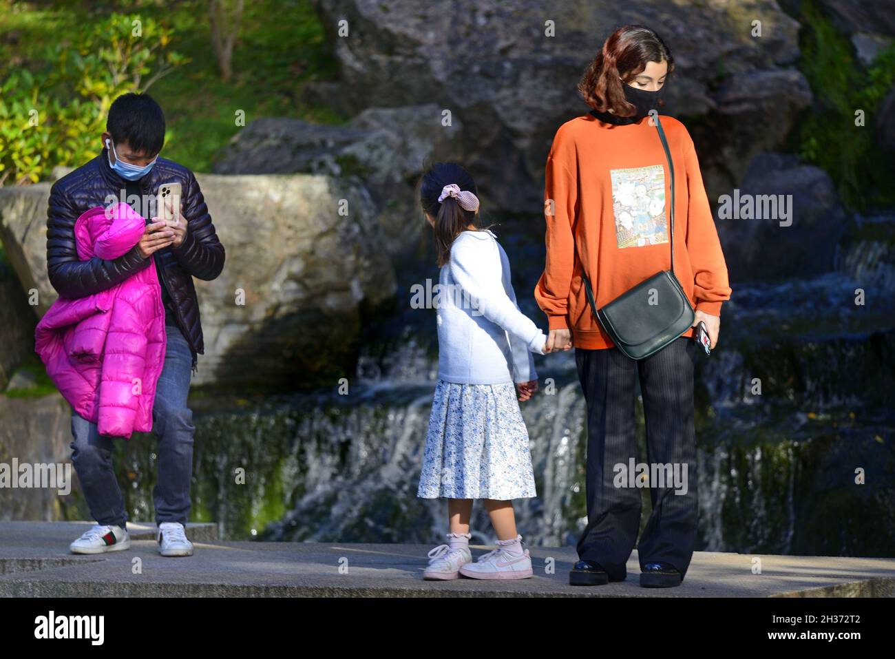 Londres, Angleterre, Royaume-Uni.Jardin de Kyoto, Holland Park.Famille asiatique avec une jeune fille près de l'étang Banque D'Images