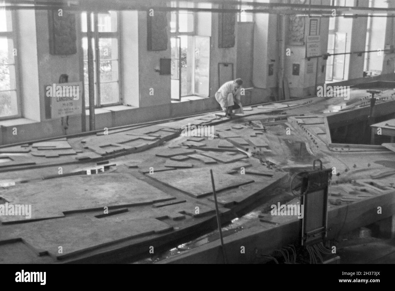 Flußbau Im Laboratorium à Karlsruhe wird ein Modell eines Staudamms durch einen Modellbauer modelliert, Deutschland 1930 er Jahre. Au laboratoire de génie de la rivière à Karlsruhe un modèle d'un barrage de la rivière est construit par un modéliste, Allemagne 1930. Banque D'Images