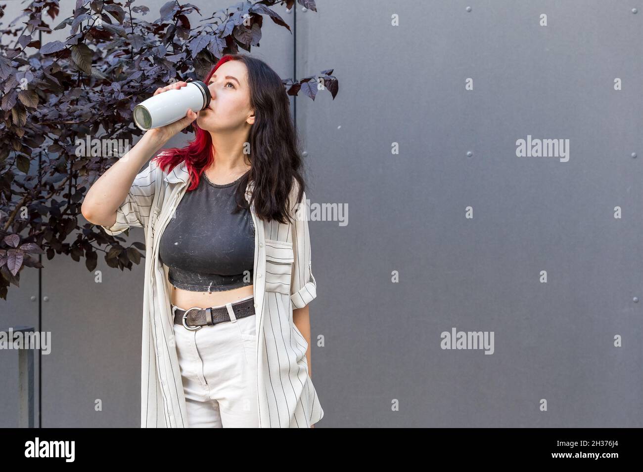 Jeune femme buvant dans le mug isotherme réutilisable.Concept de rester hydraté Banque D'Images