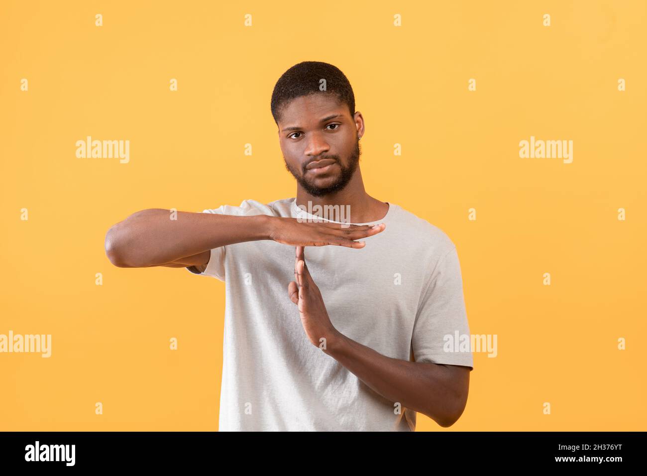 Afro-américain gars montrant LE TEMPS DE PAUSE ou D'ARRÊT de geste de pause ou de pause, arrière-plan jaune de studio, Banque D'Images
