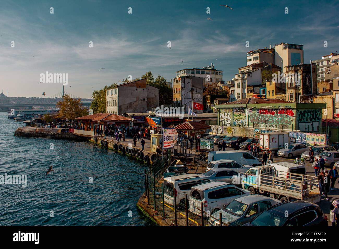 Eminonu,Istanbul,Turquie-octobre-samedi-2021: Temps nuageux, voitures garées.personnes marchant parmi les vieilles maisons.Dessin Graffiti.Golden Horn Metro Bridge Banque D'Images