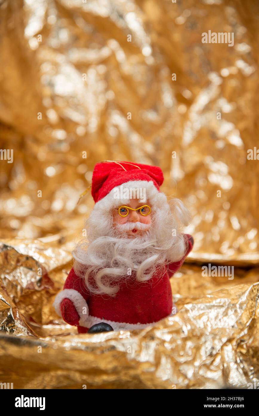 Jouet du Père Noël avec un costume rouge et un chapeau, une barbe blanche et des verres dorés, isolé sur un fond orange brillant avec bokeh.Joyeux Noël Banque D'Images