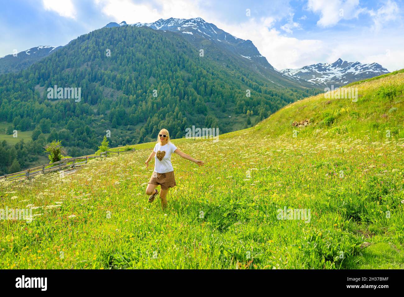 Femme insouciante heureuse avec une jupe courte dans la campagne de Guarda village de Scuol en Suisse.Ville de Guarda près de l'Auberge de la rivière de Suisse Banque D'Images