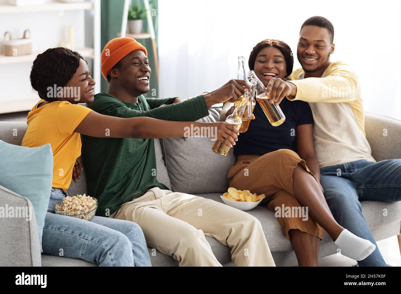 Joyeux amis noirs qui applaudissent avec des bouteilles de bière Banque D'Images
