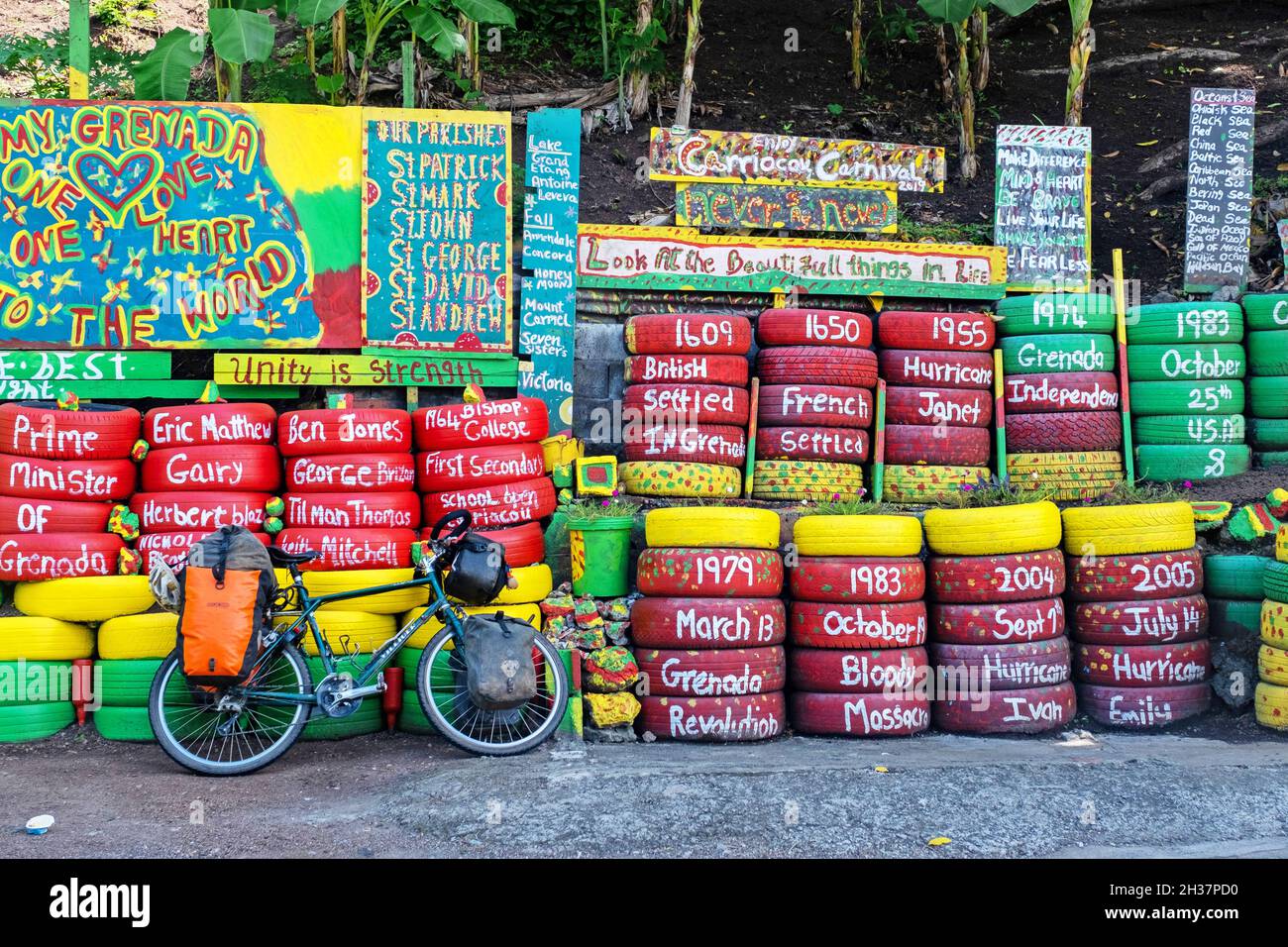 Mur de pneus de voiture aux couleurs de la Grenade sur Happy Hill en face de Charlie's bar, Saint George sur la côte ouest de l'île de Grenade, Caraïbes Banque D'Images
