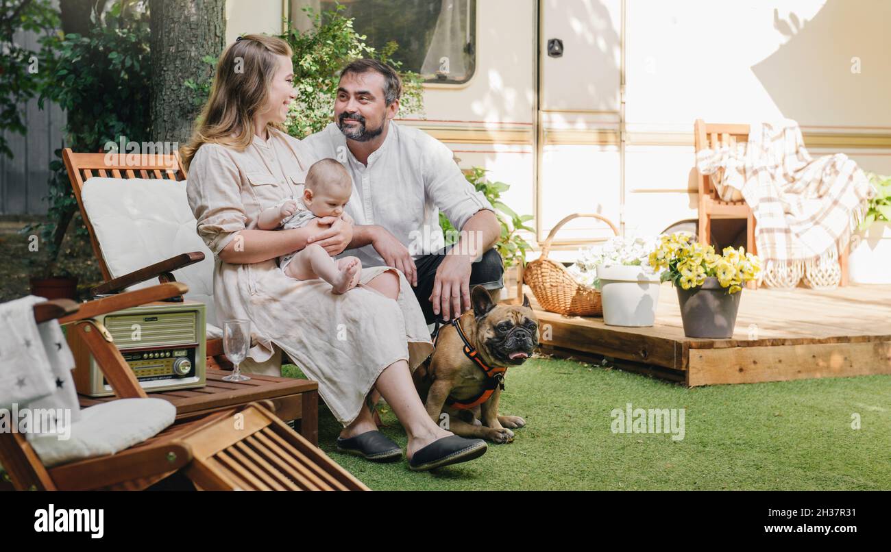 Famille avec bébé et chien passer du temps heureux ensemble près de la remorque à l'extérieur sur la chaise de pont, le style de vie de voyage avec campeur Banque D'Images