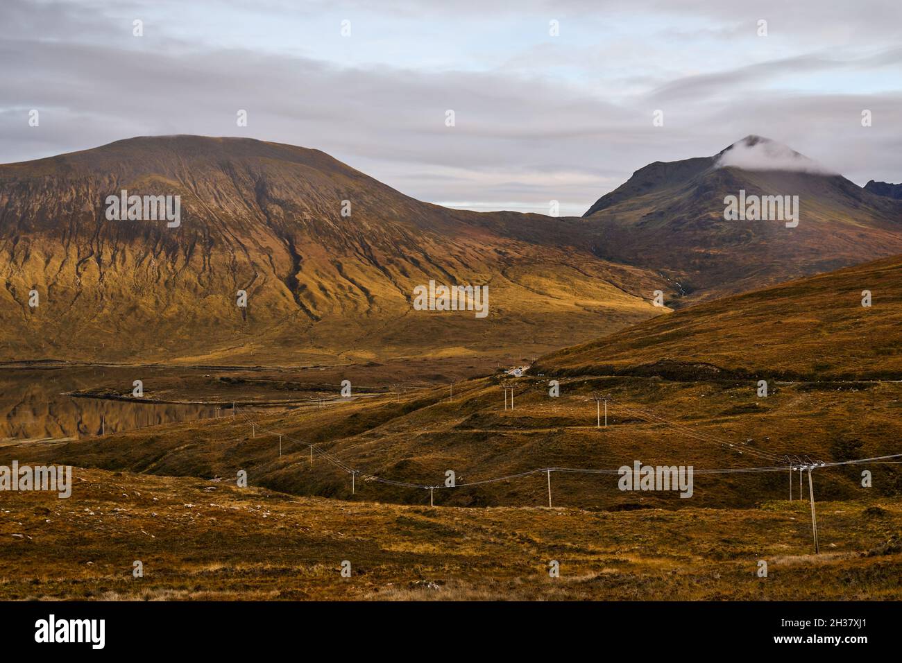 La lumière du soleil frappe les montagnes, y compris Ben Na Cro, au-dessus d'un Loch Ainort vitreux, île de Skye. Banque D'Images