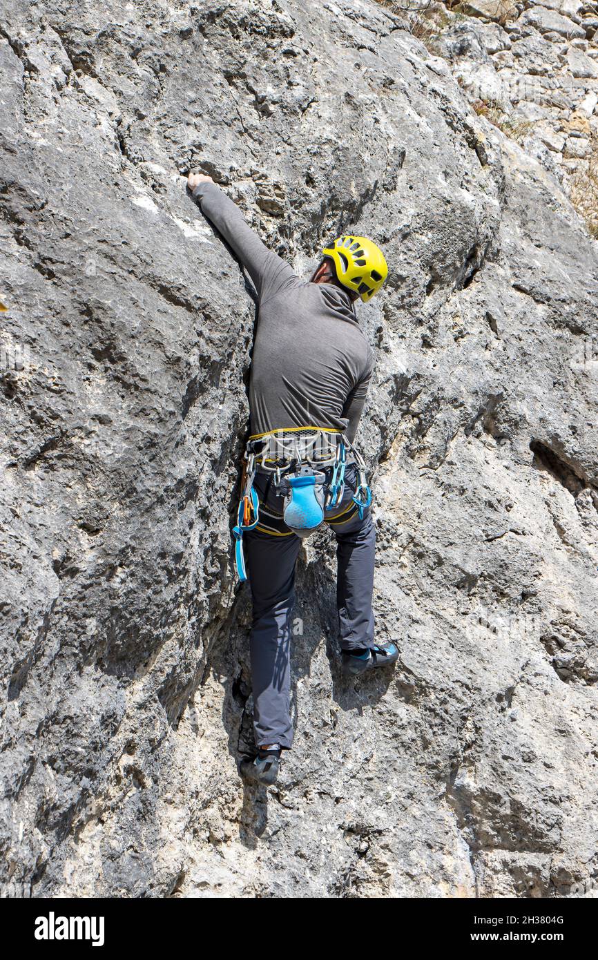 Jeune homme sportif grimpant haut mur rocheux naturel sur Kalnik, Croatie Banque D'Images