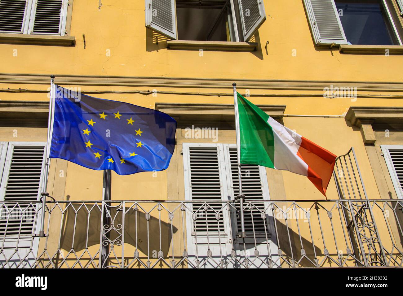 Union européenne drapeau de l'UE et de l'Italie sur des poteaux agitant dans le vent avec un manoir italien classique en arrière-plan Banque D'Images