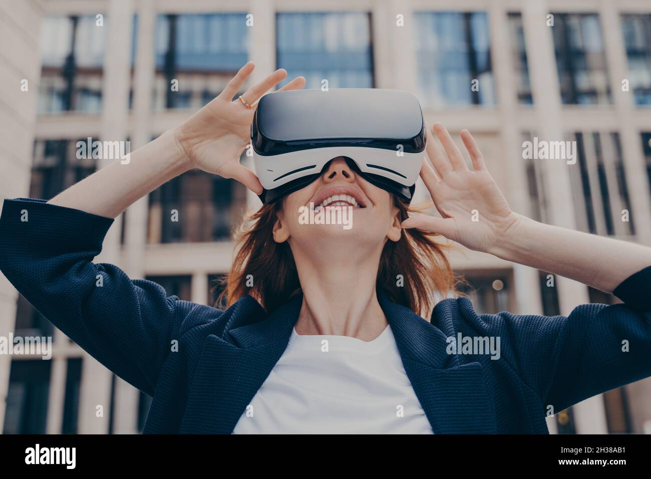 Femme plongée dans la réalité virtuelle tout en portant un VR portable, debout dans la rue de la ville Banque D'Images