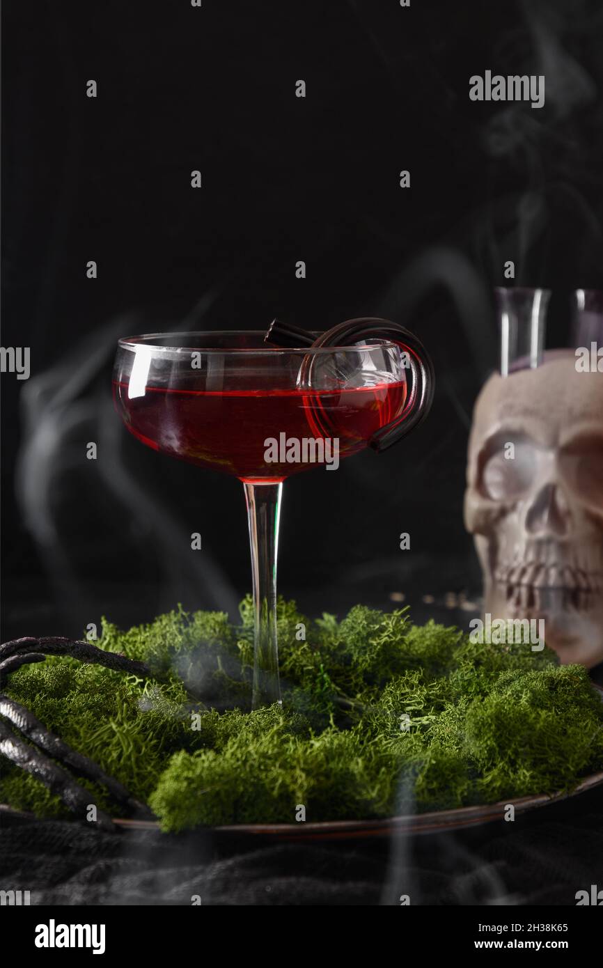 Cocktail alcoolique rouge Halloween et crâne avec fumée sur fond noir.Horreur nourriture drôle pour la fête de nuit. Banque D'Images